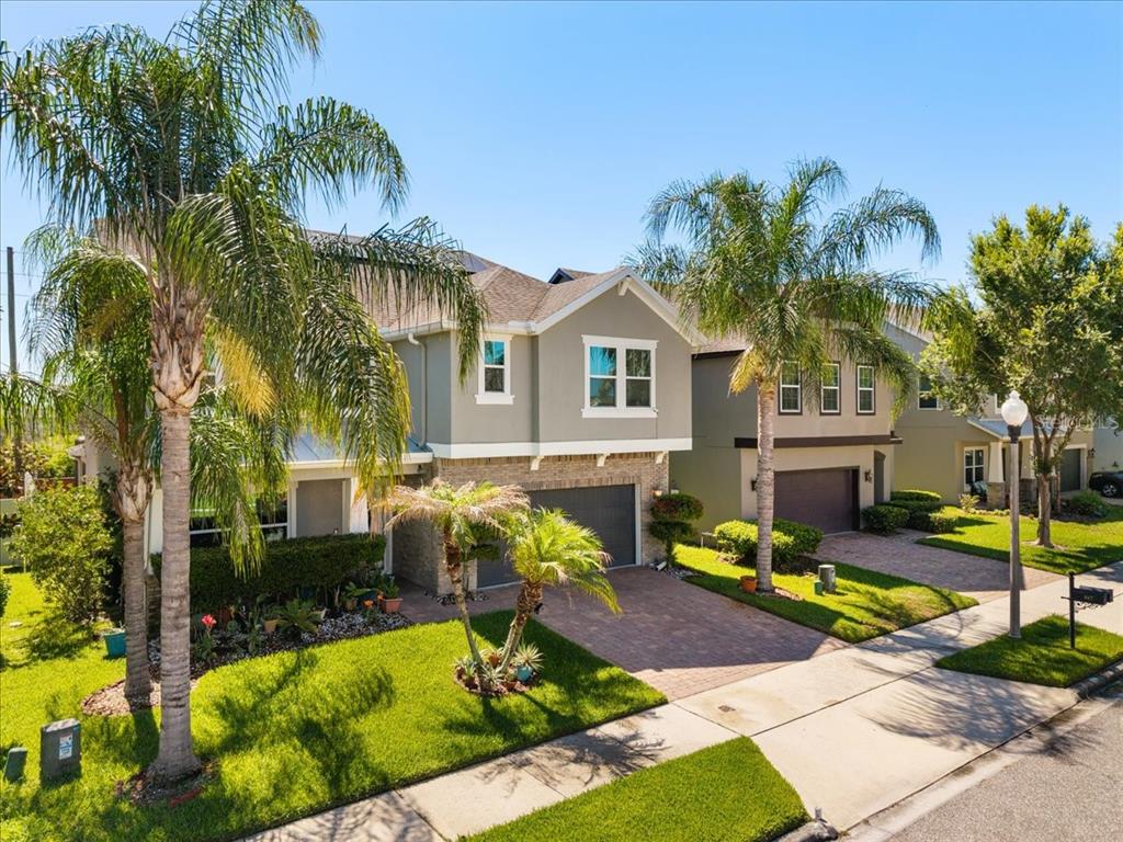 Two-story suburban houses with gray siding, stone accents, and palm trees in the front yards — 617 MARSH REED DRIVE, WINTER GARDEN, FL