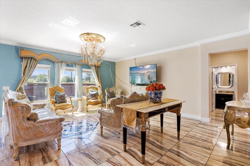 A living room features ornate furniture, a crystal chandelier, and polished tile flooring — 617 MARSH REED DRIVE, WINTER GARDEN, FL