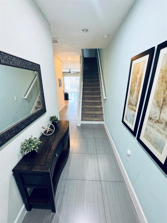 A hallway features light blue walls, tile flooring, a console table, and a staircase — 17531 PLACIDITY AVENUE, CLERMONT, FL