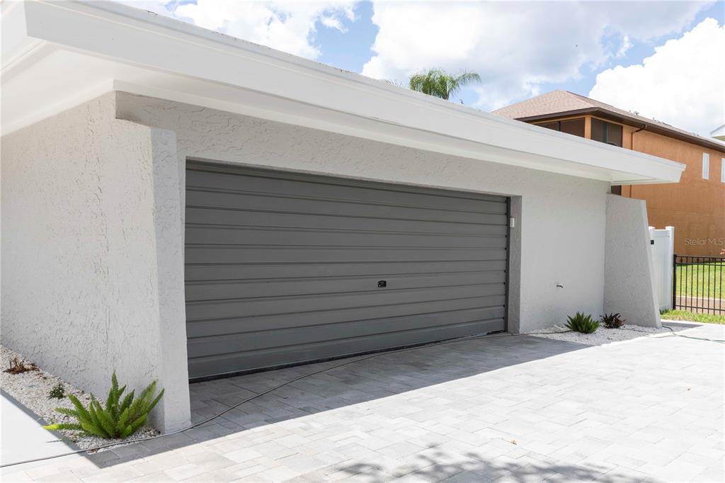 A gray garage door is set into a white stucco exterior with a paved driveway — 5303 SEA FOREST DRIVE, NEW PORT RICHEY, FL