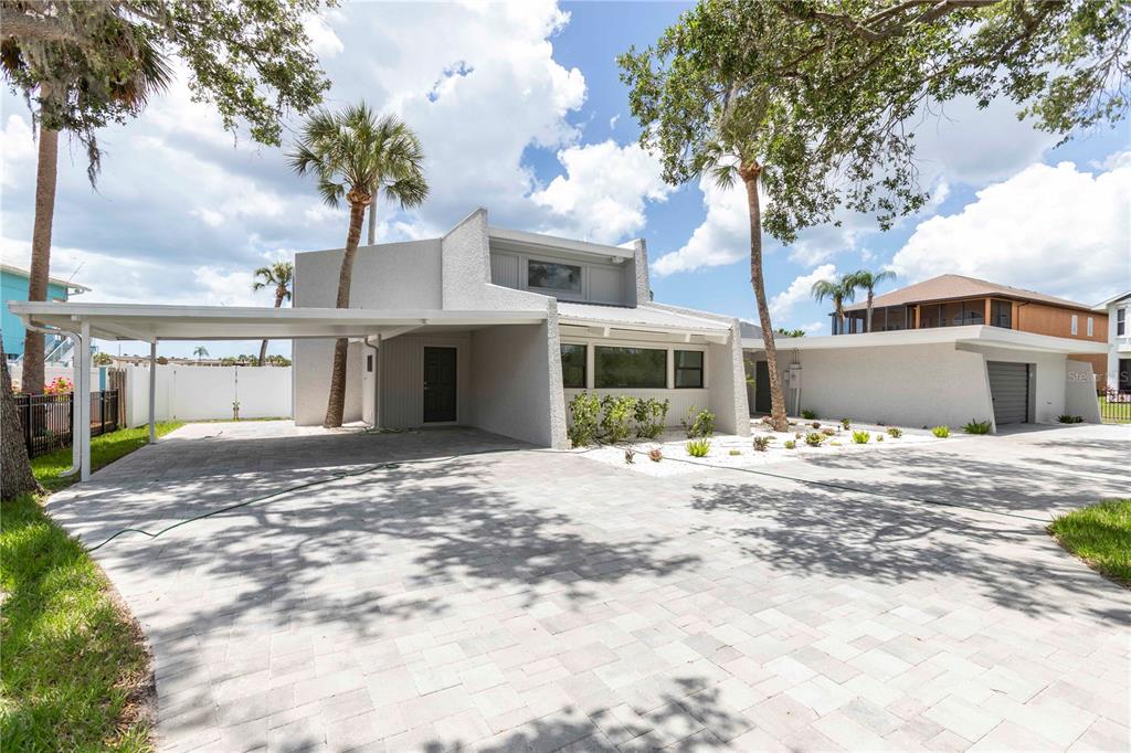 A modern two-story house with a paved driveway, carport, and attached garage under a blue sky — 5303 SEA FOREST DRIVE, NEW PORT RICHEY, FL