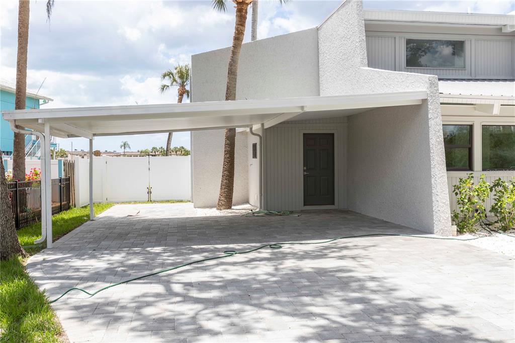 A paved carport with a white metal roof is attached to a white stucco house — 5303 SEA FOREST DRIVE, NEW PORT RICHEY, FL