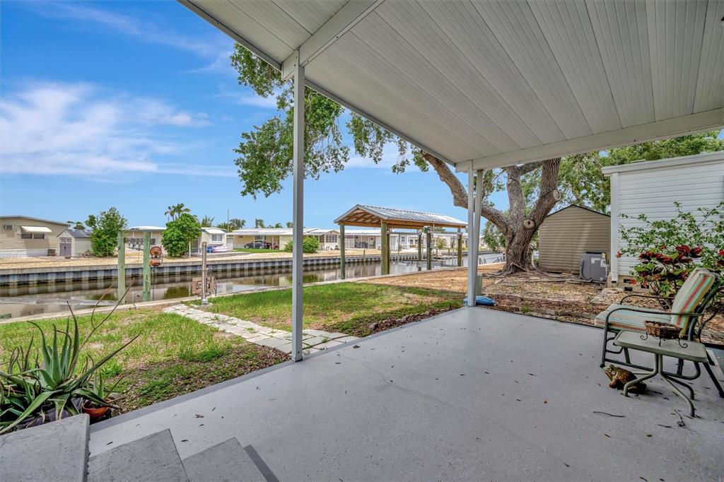 A covered patio overlooks a canal with a boat dock and neighboring mobile homes — 106 N SAINT GEORGE CIRCLE, APOLLO BEACH, FL