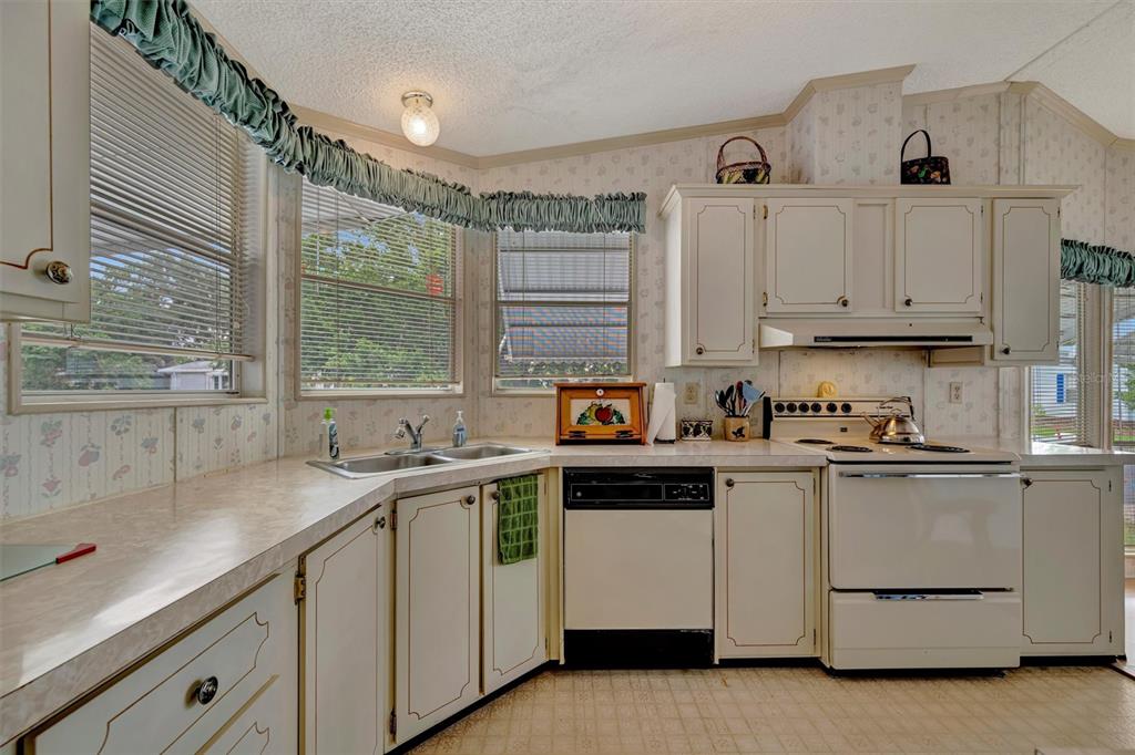 A kitchen features white cabinets, laminate countertops, a double sink, and a white stove — 106 N SAINT GEORGE CIRCLE, APOLLO BEACH, FL