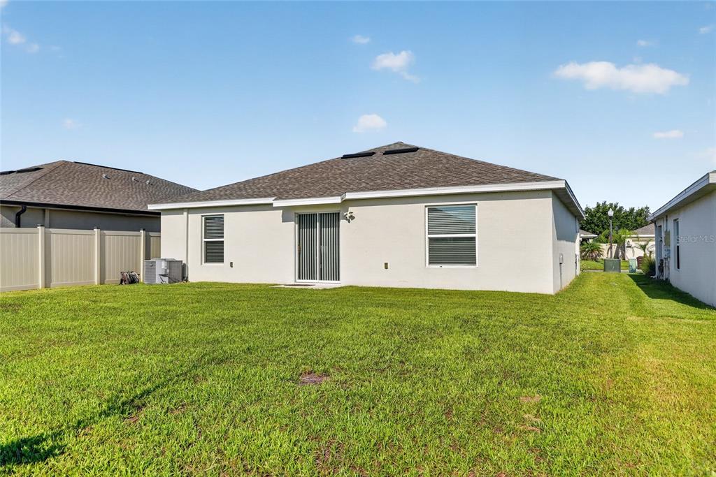 A single-story house with a beige stucco exterior, a two-car garage, and a front lawn — 5151 FOUR STRAND COURT, ST CLOUD, FL