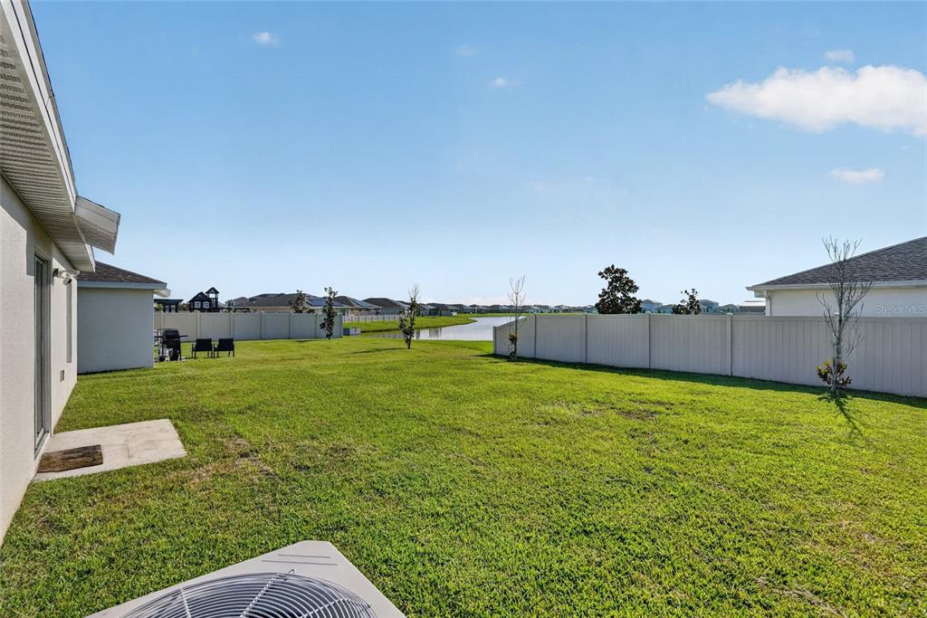 A single-story suburban house with a beige stucco exterior, a two-car garage, and a lawn — 5151 FOUR STRAND COURT, ST CLOUD, FL