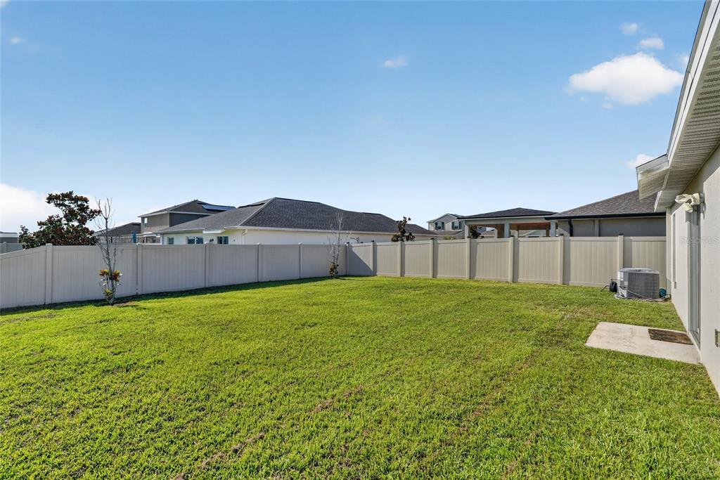 A single-story house with a beige stucco exterior, blue shutters, and a front lawn — 5151 FOUR STRAND COURT, ST CLOUD, FL