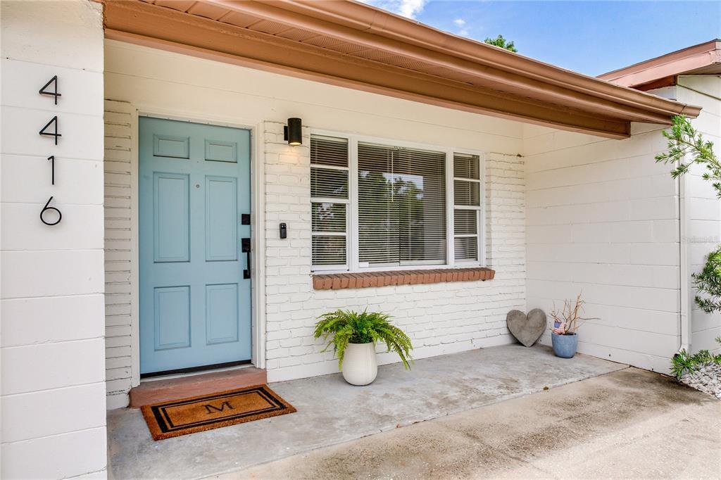 A light blue front door sits next to a window on a white brick porch — 4416 W BAY COURT AVENUE, TAMPA, FL