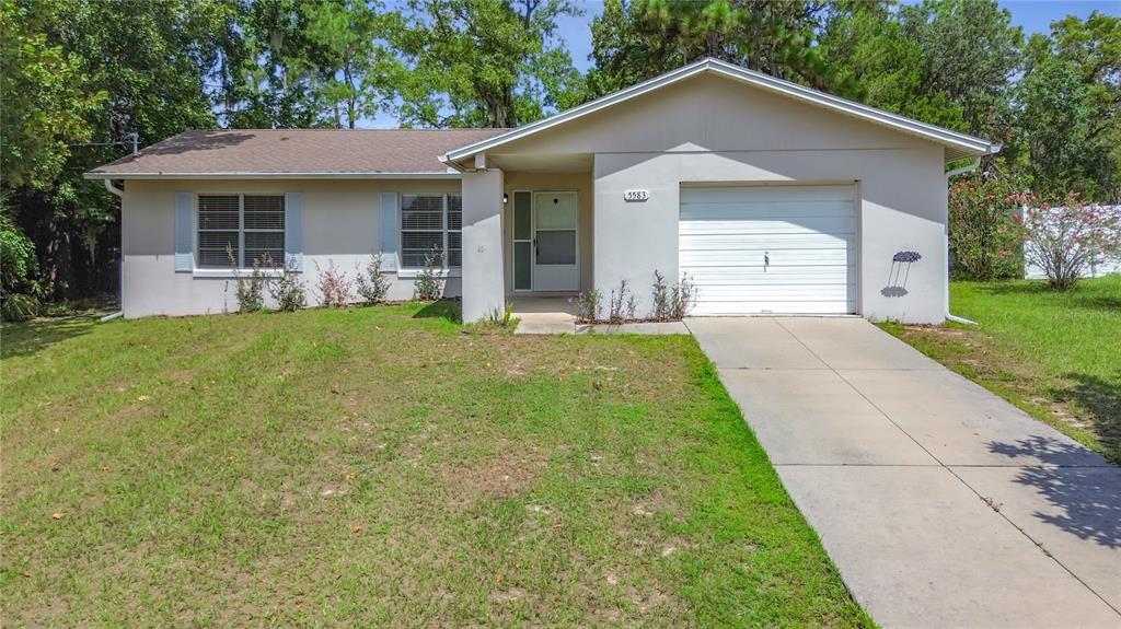 A single-story house with a white stucco exterior, a one-car garage, and a concrete driveway — 5583 W CAGNEY LOOP, HOMOSASSA, FL