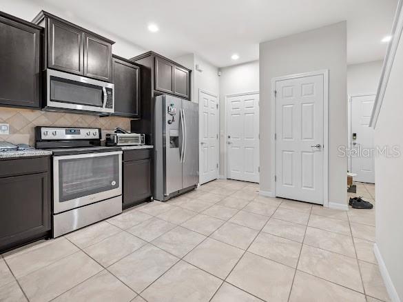 A kitchen with dark wood cabinets, stainless steel appliances, and light-colored tile flooring — 9157 HILLCROFT DRIVE, RIVERVIEW, FL