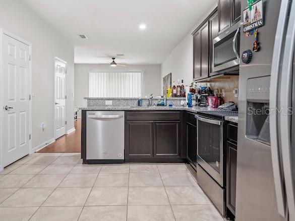 A kitchen with dark wood cabinets, stainless steel appliances, and a granite countertop breakfast bar — 9157 HILLCROFT DRIVE, RIVERVIEW, FL