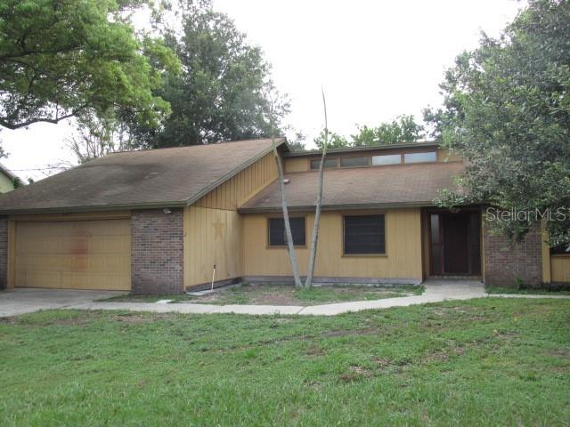 A single-story house with a two-car garage, brick accents, and vertical wood siding — 2617 HOMEWOOD DRIVE, BELLE ISLE, FL