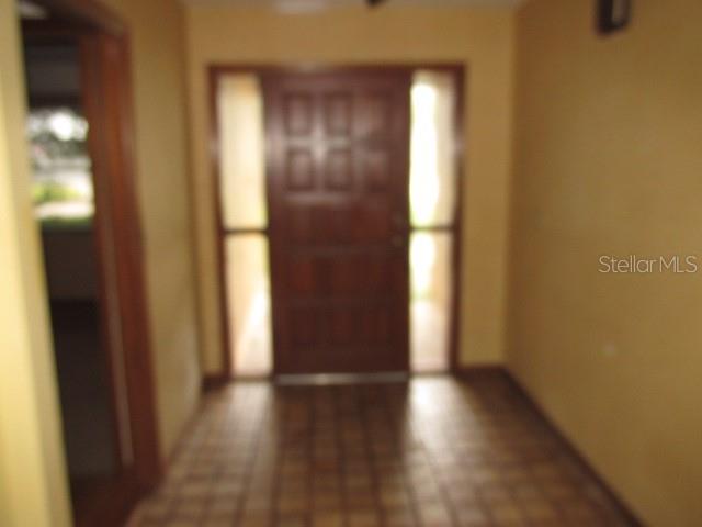 A foyer with tiled flooring features a wooden front door flanked by two vertical windows — 2617 HOMEWOOD DRIVE, BELLE ISLE, FL