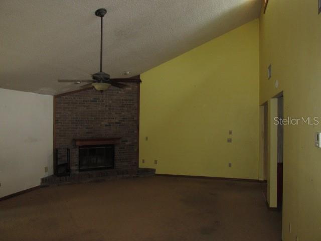A living room features a brick fireplace, a ceiling fan, and yellow vaulted walls — 2617 HOMEWOOD DRIVE, BELLE ISLE, FL