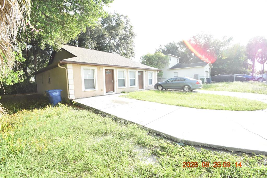 A single-story house with a concrete driveway and a lawn sits under a bright sky — 3506 E 10TH AVENUE UNIT 1/2, TAMPA, FL