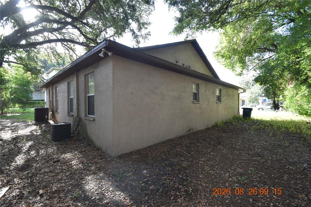 The exterior of a stucco house features several windows and two air conditioning units — 3506 E 10TH AVENUE UNIT 1/2, TAMPA, FL