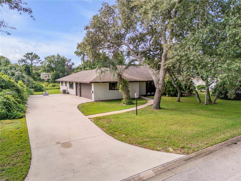 A single-story house with a concrete driveway, a two-car garage, and large oak trees — 530 CLUB HOUSE BOULEVARD, NEW SMYRNA BEACH, FL