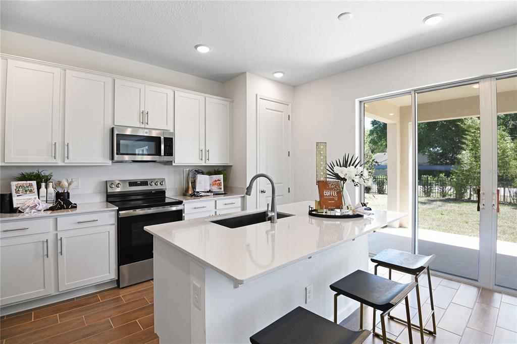 A dining area with a dark table and chairs opens to a living room beyond — 172 FLAG LILLY LANE, UMATILLA, FL
