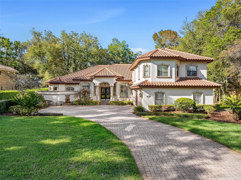 A two-story Mediterranean-style house with a tile roof and a paved driveway at dusk — 7341 BELLA FORESTA PLACE, SANFORD, FL