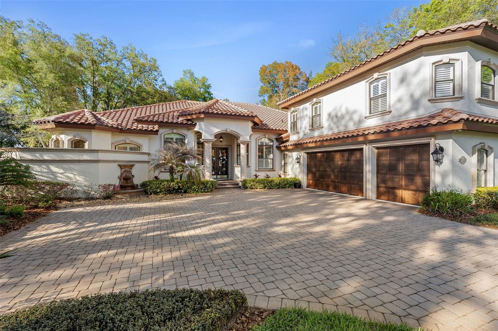 A two-story stucco house with a tile roof and a large paver driveway — 7341 BELLA FORESTA PLACE, SANFORD, FL