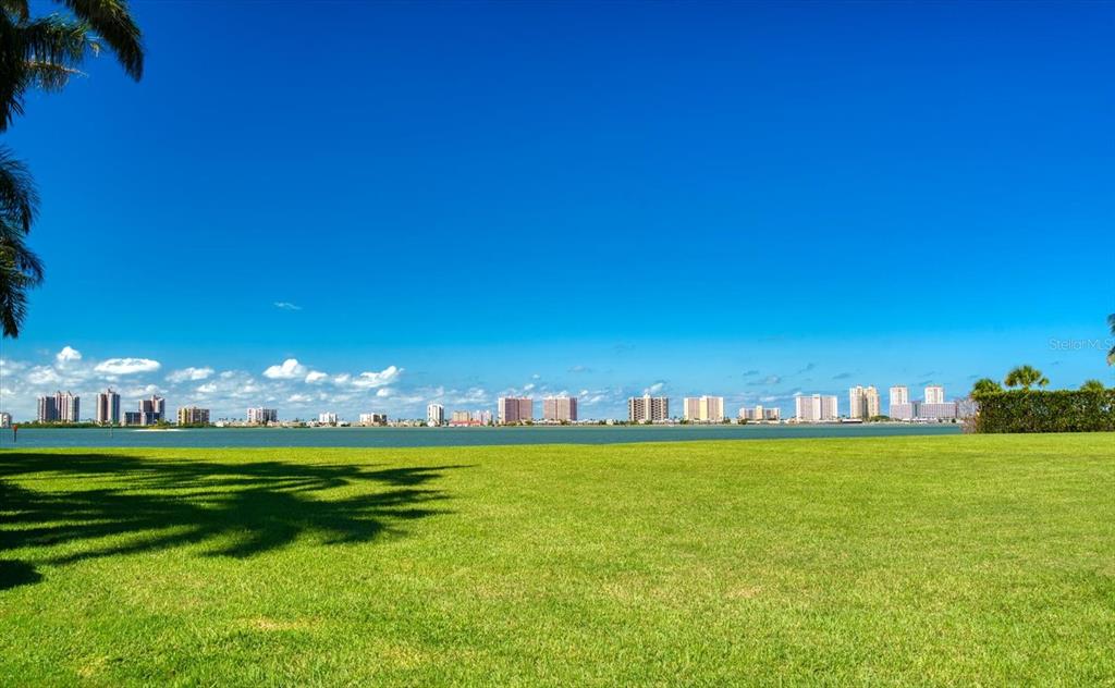A wide, grassy lawn overlooks a body of water with a distant city skyline — ST ANDREWS DRIVE, BELLEAIR, FL