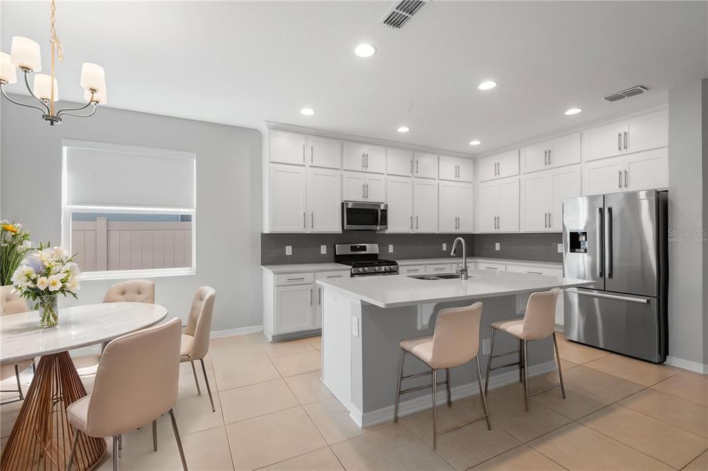 A modern kitchen features white cabinetry, stainless steel appliances, a center island, and tile flooring — 2017 BOSS HEWETT STREET, OAKLAND, FL