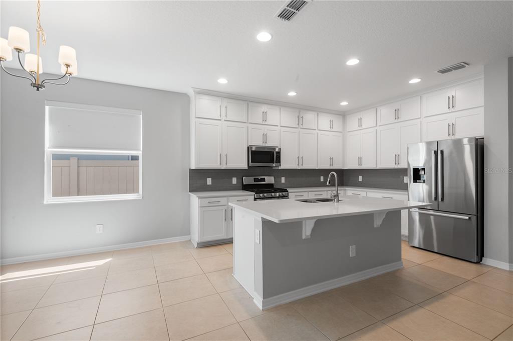 A living room features a wall-mounted television, white furniture, carpeted flooring, and sliding glass doors — 2017 BOSS HEWETT STREET, OAKLAND, FL