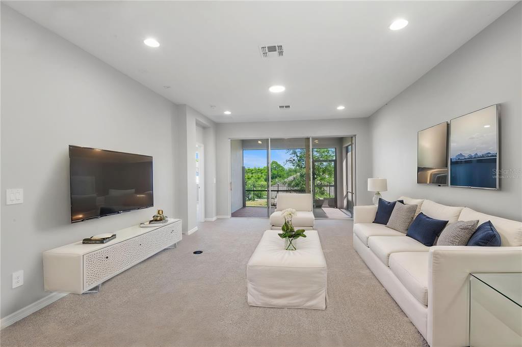 A spacious living room with neutral carpet, light gray walls, recessed lighting, and a sliding door — 2017 BOSS HEWETT STREET, OAKLAND, FL