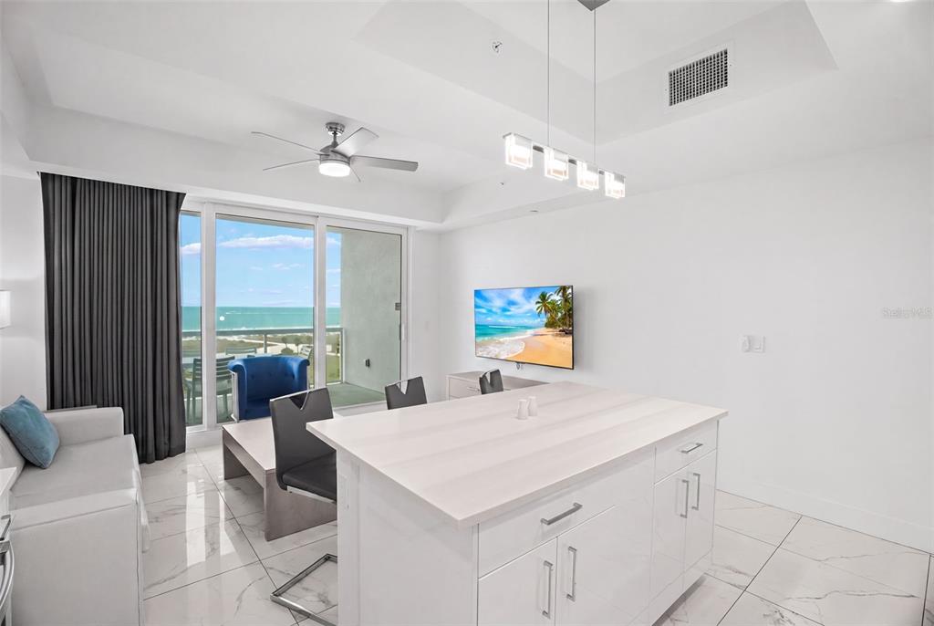 A modern kitchen island and living area feature white marble floors and a beach view — 11500 GULF BOULEVARD UNIT 603, TREASURE ISLAND, FL