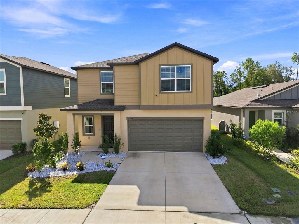 A two-story house with a tan exterior, a gray garage door, and a concrete driveway — 35418 ACKLEY TRACE, ZEPHYRHILLS, FL