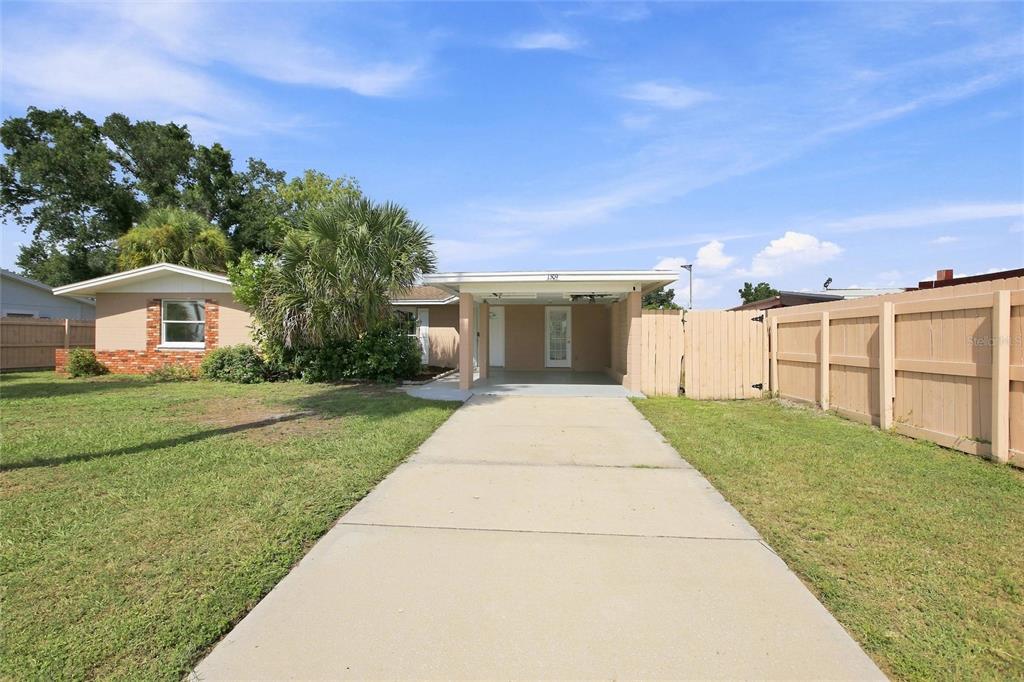 A single-story house with a concrete driveway, a covered carport, and a wooden privacy fence — 1509 BANYAN DRIVE, VENICE, FL