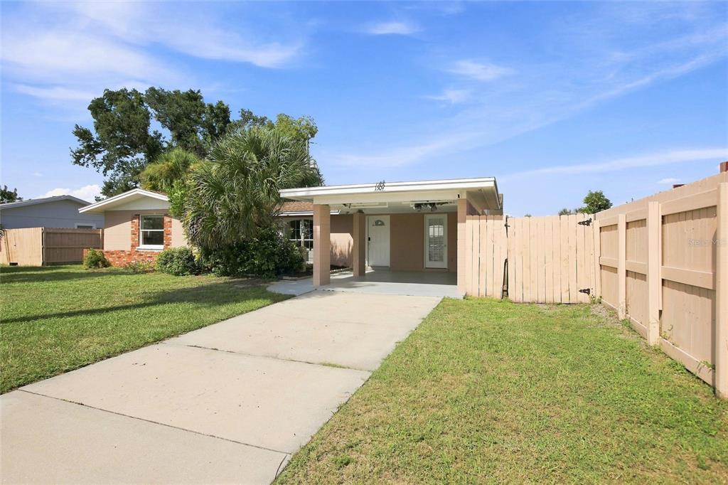 A single-story house with a carport, concrete driveway, and a tan wooden privacy fence — 1509 BANYAN DRIVE, VENICE, FL