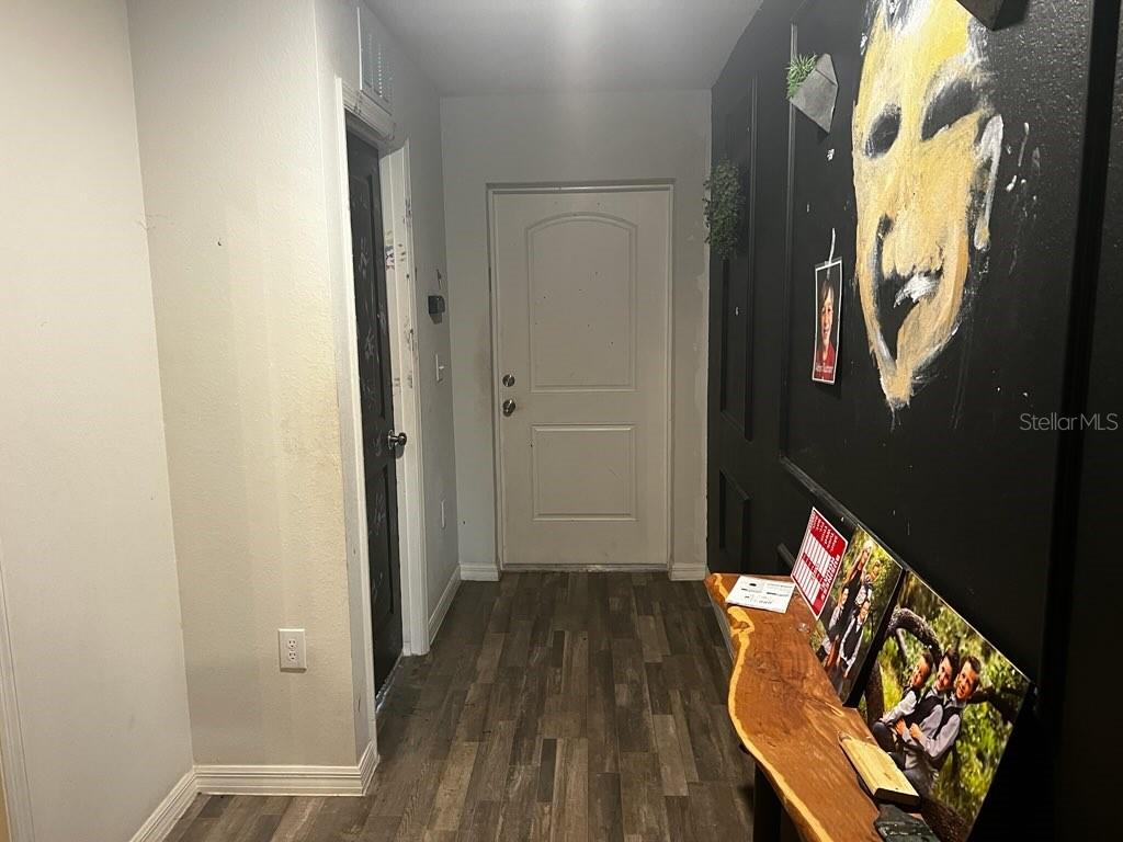A hallway features wood-look flooring, a black accent wall with artwork, and a white door — 30398 BEECH ROAD, PUNTA GORDA, FL