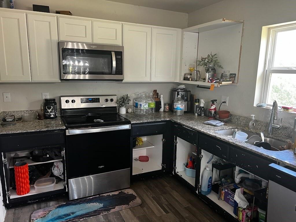 A kitchen features white upper cabinets, black lower cabinets without doors, and granite countertops — 30398 BEECH ROAD, PUNTA GORDA, FL