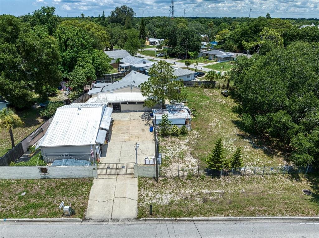 An aerial view shows a house with a large concrete driveway and a fenced yard — 1769 OVERBROOK AVENUE, CLEARWATER, FL