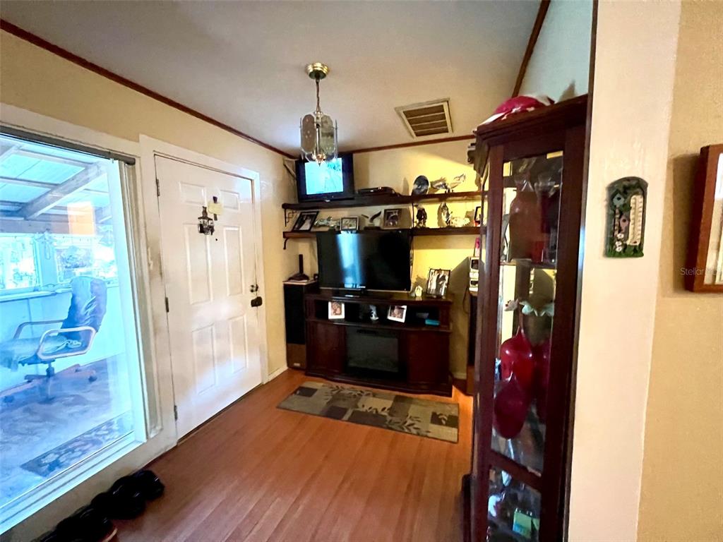 A living room features a television console, a glass display cabinet, and a white door — 1769 OVERBROOK AVENUE, CLEARWATER, FL