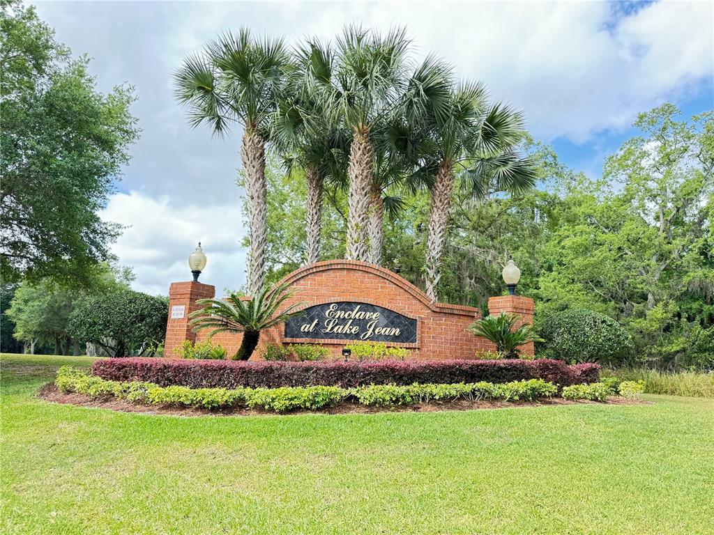 A brick monument sign for Enclave at Lake Jean stands behind a landscaped garden bed — 2971 LAKE JEAN DRIVE, ORLANDO, FL
