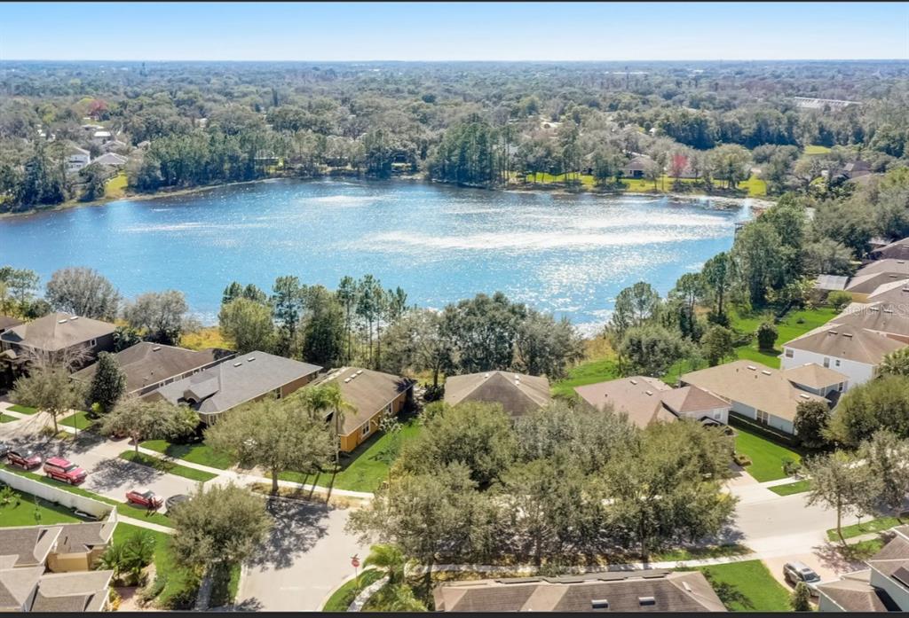 An aerial view shows suburban houses surrounding a large lake with trees and blue sky — 2971 LAKE JEAN DRIVE, ORLANDO, FL