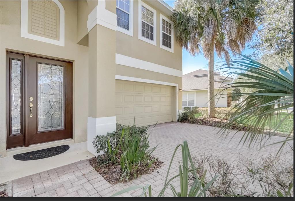 A beige two-story house exterior with a brown front door, garage, and paved driveway — 2971 LAKE JEAN DRIVE, ORLANDO, FL