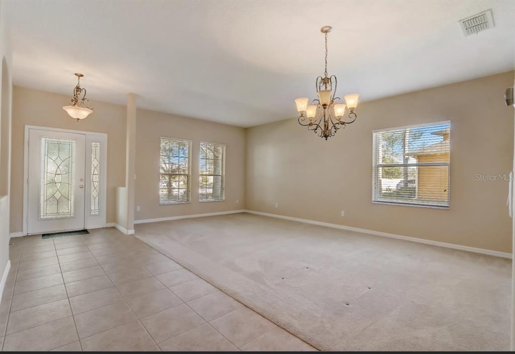 An entryway with tile flooring leads into a carpeted living room featuring a chandelier — 2971 LAKE JEAN DRIVE, ORLANDO, FL