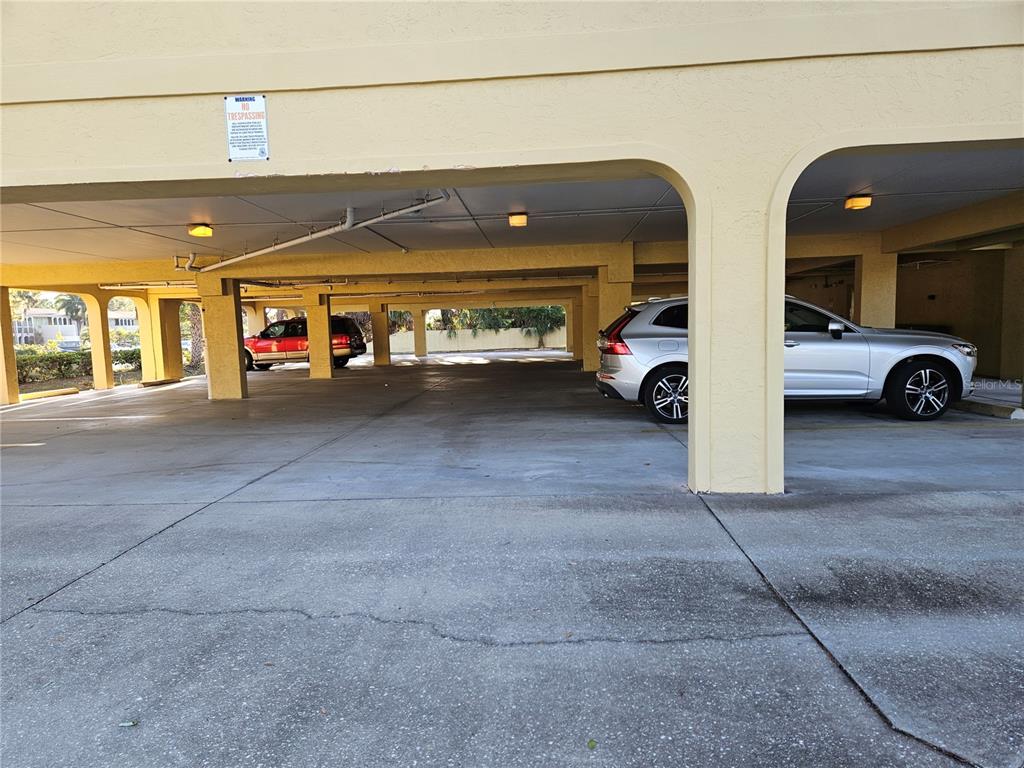 A covered parking area features concrete pillars, overhead lighting, and two parked vehicles — 2389 RINGLING BOULEVARD UNIT A, SARASOTA, FL