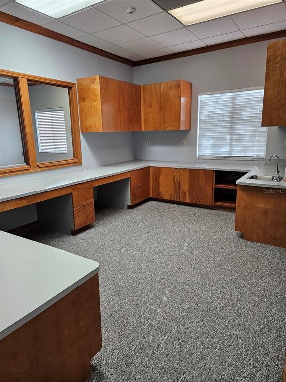 An office or break room featuring wood cabinets, light countertops, a sink, and carpeted floors — 2389 RINGLING BOULEVARD UNIT A, SARASOTA, FL
