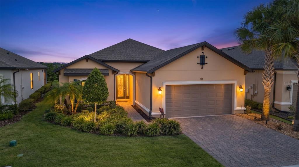 A single-story house with a beige stucco exterior, a two-car garage, and a paved driveway — 908 BRAEWOOD DRIVE, CLERMONT, FL