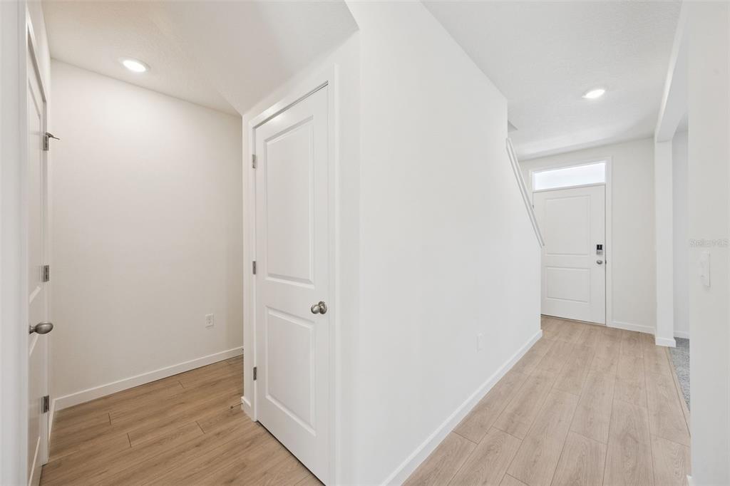 A bright entryway features light wood-look flooring, white walls, and two closed interior doors — 1103 GULL DRIVE, APOPKA, FL