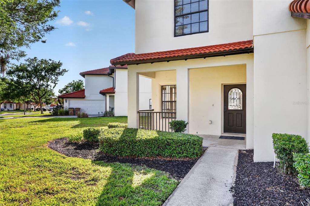 The exterior of a two-story home features a covered entryway, a brown door, and landscaping — 126 SUMMER PLACE LOOP, CLERMONT, FL