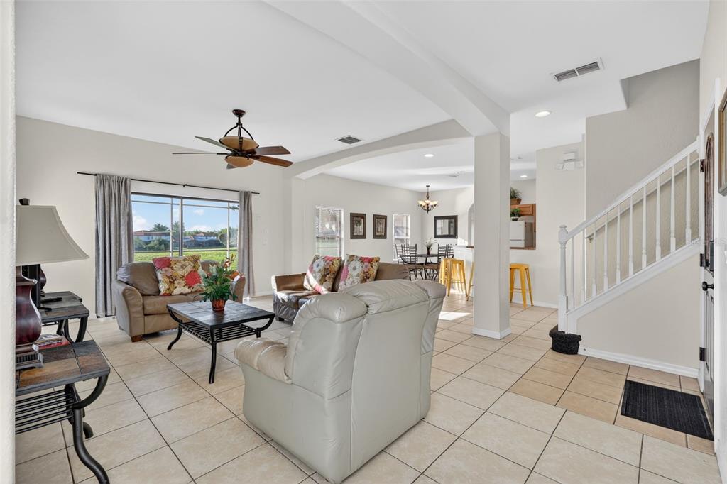 An open-concept living room features tile floors, a ceiling fan, and a staircase — 126 SUMMER PLACE LOOP, CLERMONT, FL