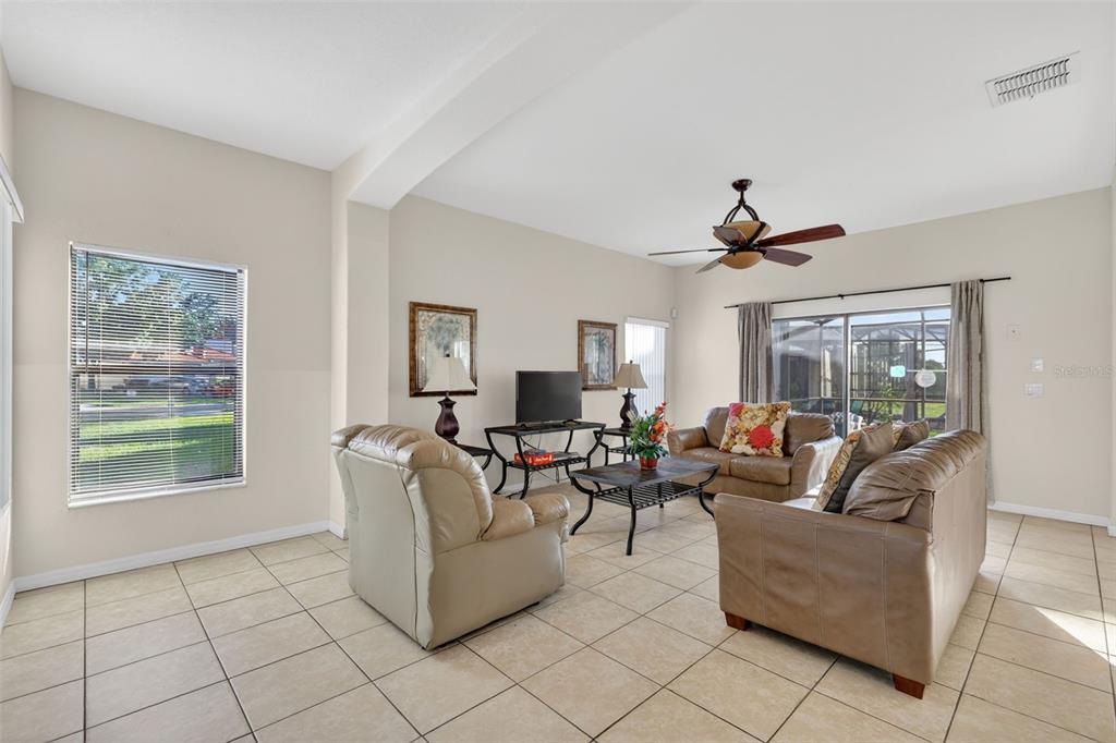 A living room features light tile floors, beige walls, a ceiling fan, and leather furniture — 126 SUMMER PLACE LOOP, CLERMONT, FL