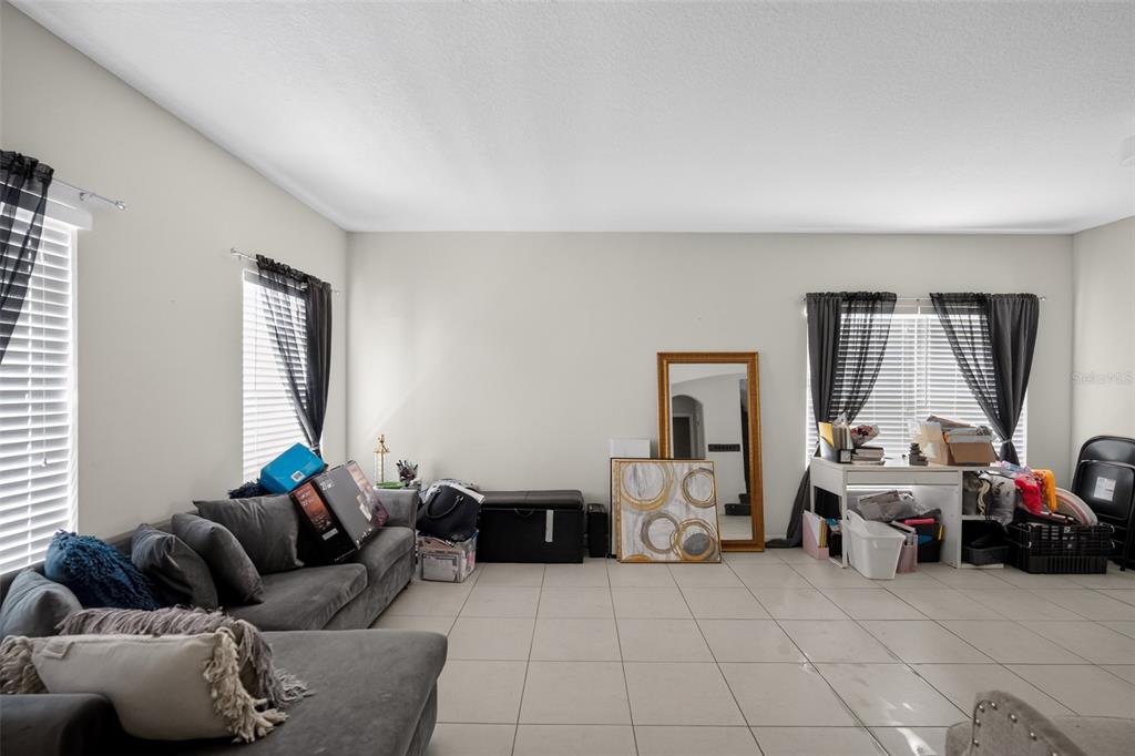 A living room with light tile floors, a gray sectional sofa, and various storage items — 11202 CARRICK STONE STREET, WIMAUMA, FL