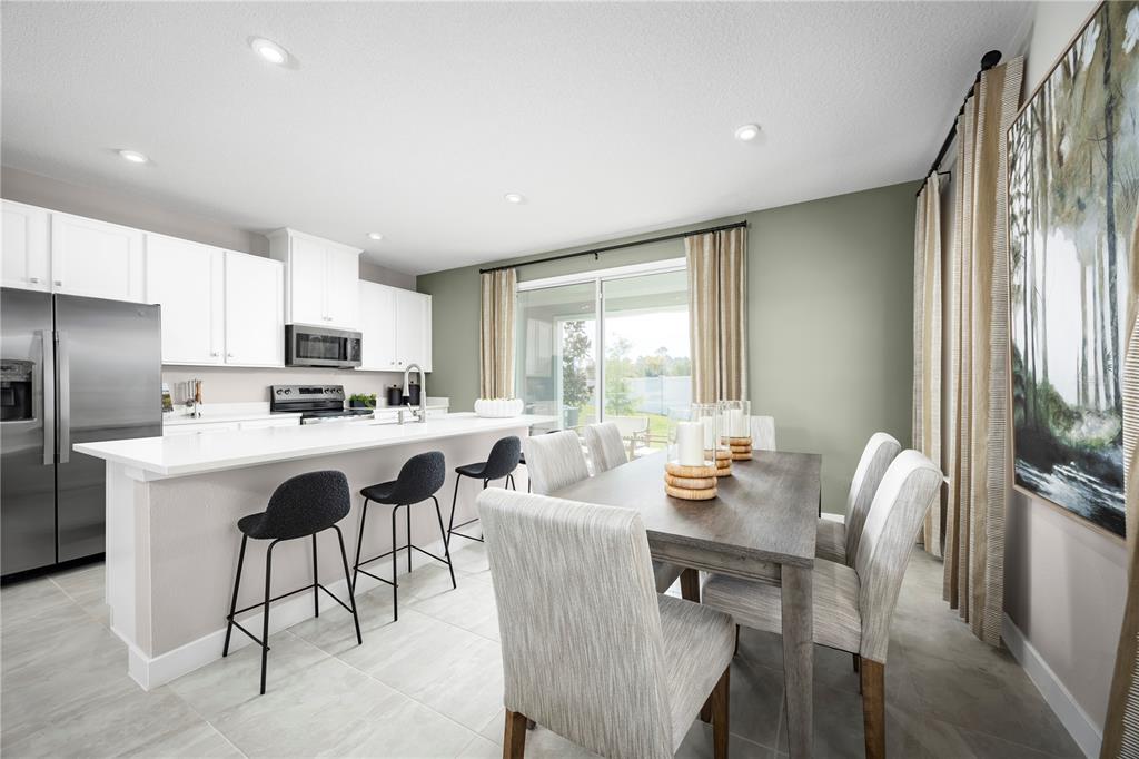 A kitchen with white cabinets and a dining area featuring a wooden table and chairs — 3994 ADDIE WAY, MELBOURNE, FL