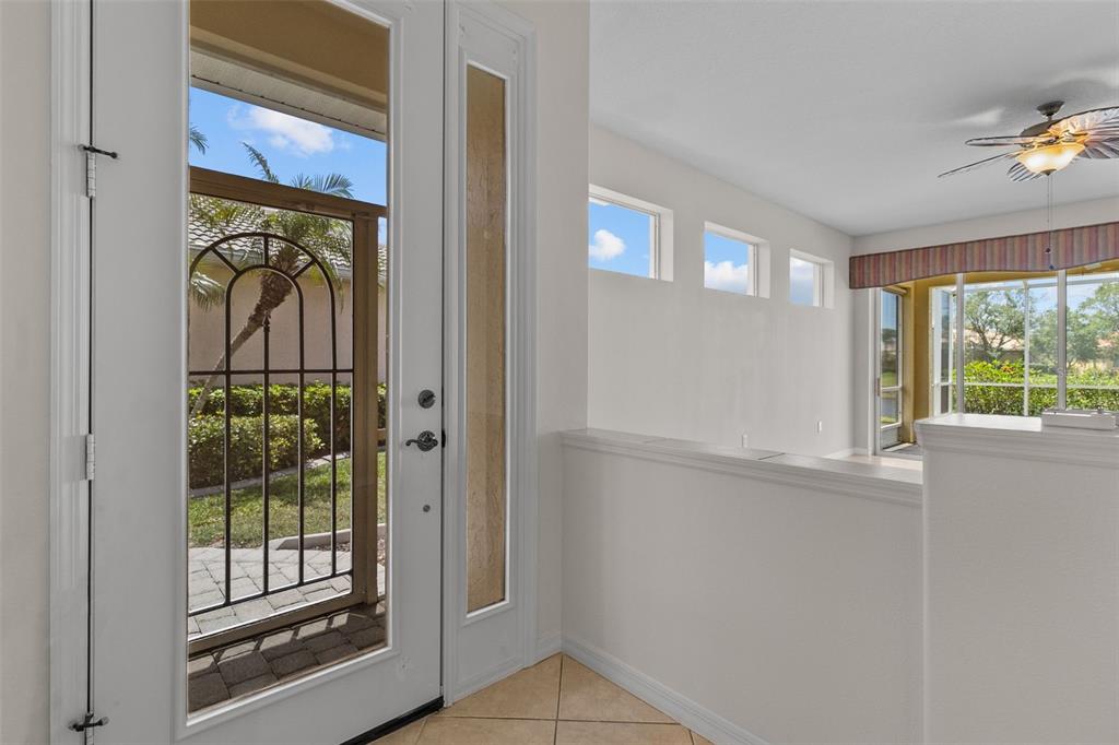 An entryway with a glass-paneled front door, tile flooring, and a view into a living area — 9486 HAWK NEST LANE, NORTH PORT, FL